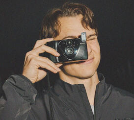 picture of formula 1 driver oscar piastri holding a camera up going to take a photo